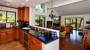 A modern kitchen with wooden cabinets, a large island, and a dining area with a view of the outdoors. - Charming Napa condo with 3 beds, garden view at Silverado (Napa)