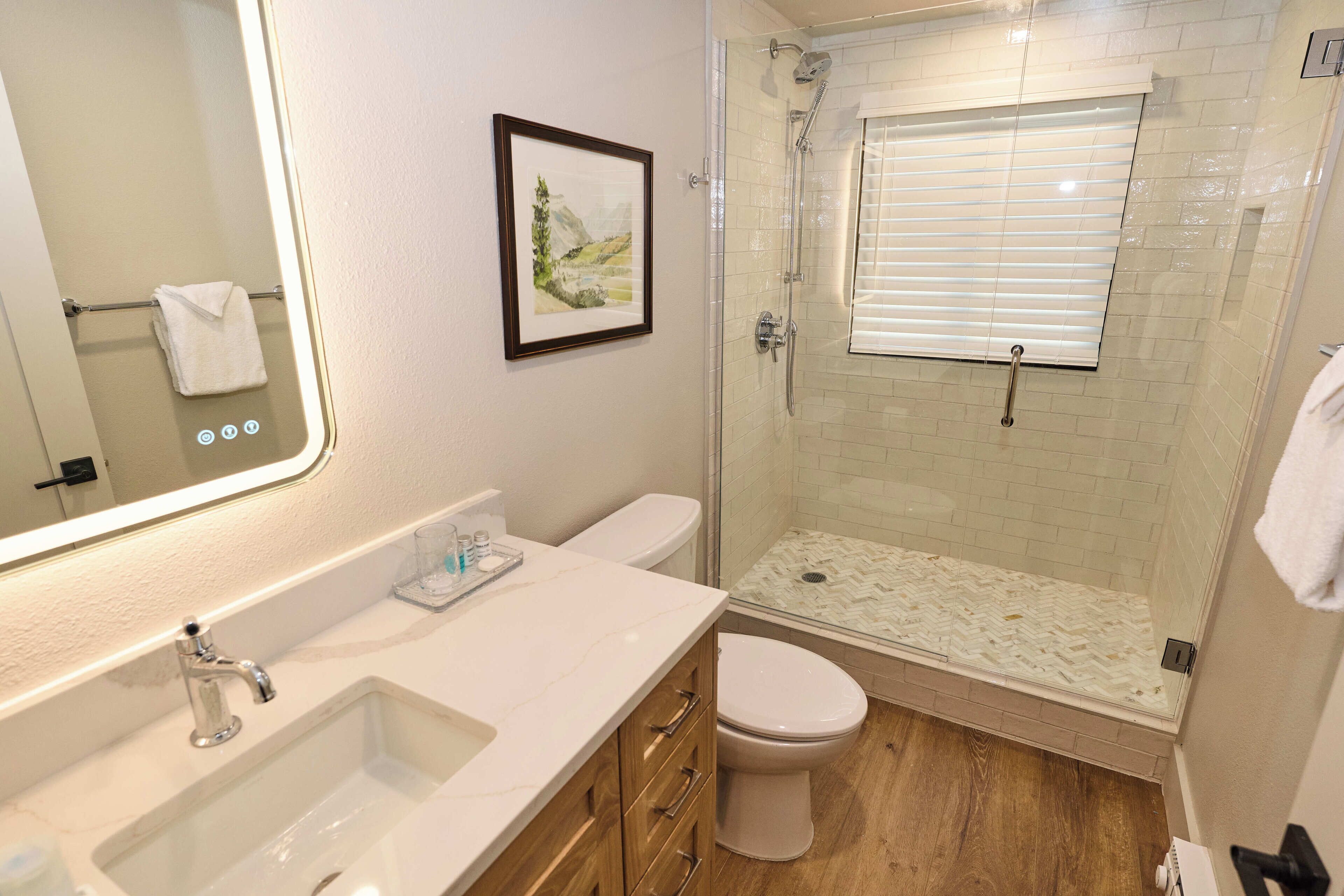 Une salle de bain équipée d’un lavabo, de toilettes et d’une douche à parois de verre.