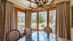 Un coin repas avec une table en verre, des fauteuils en cuir et une grande fenêtre agrémentée de rideaux.