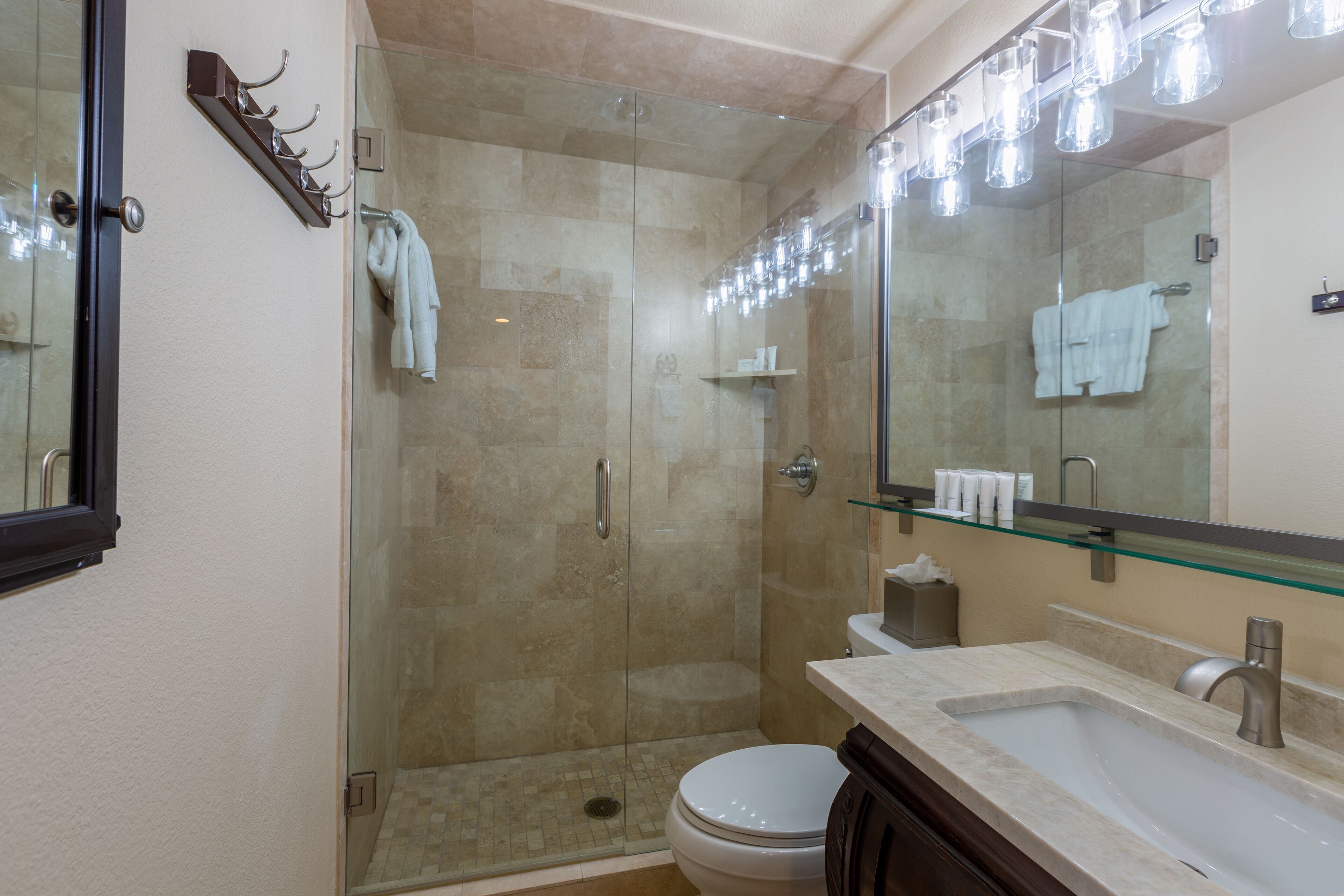 A modern bathroom with a glass-enclosed shower, a white toilet, a sink with a mirror, and a towel rack.