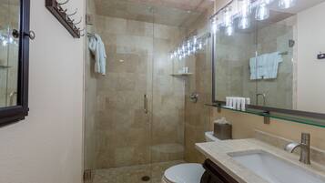 A modern bathroom with a glass-enclosed shower, a white toilet, a sink with a mirror, and a towel rack.