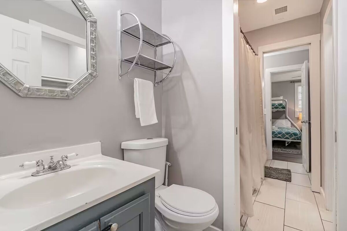 Une salle de bain avec un lavabo blanc, des toilettes et un miroir doté d’un cadre décoratif.
