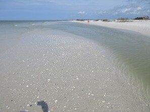 Ein Strand mit klarem, flachen Wasser und einem Sandufer.