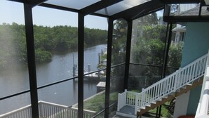 A covered outdoor swimming pool with a view of a lake and a staircase leading to a deck.