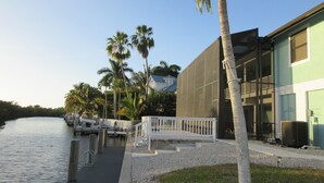 A waterfront property with a dock, palm trees, and a modern building with large windows.