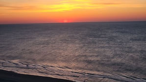 Un coucher de soleil sur une mer calme, avec un horizon lointain.