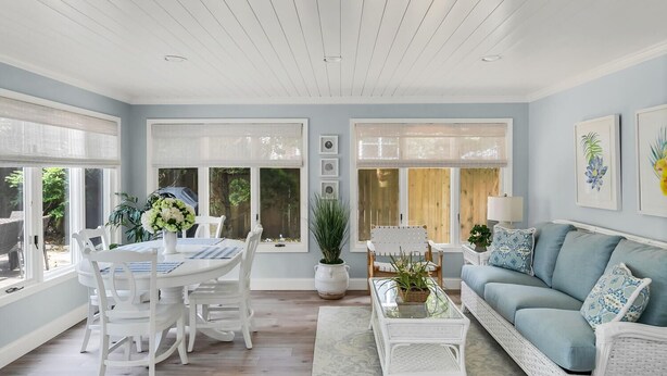 A spacious living room with a light blue sofa, white wicker furniture, and large windows with blinds. - Newly renovated upscale Beach House  (Bay Head)