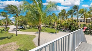 Blick auf ein Hotel mit Palmen, einer Flagge und einem gepflasterten Weg.