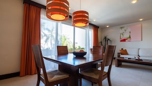 A dining area with a wooden table, four chairs, and two pendant lights.