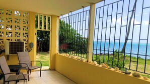 Un balcón con vistas al mar, suelo de baldosas y una mesa con sillas.