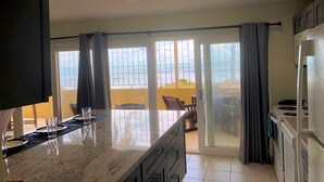 Una cocina con una isla grande, un comedor con vistas y una puerta corrediza que da a un balcón.