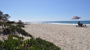 Une plage avec une chaise et un parasol, la mer et un ciel dégagé.