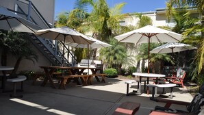 Un espace extérieur aménagé en terrasse, avec des tables et des chaises, des parasols et un escalier.