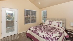 A bedroom with a large bed, a ceiling fan, and a door with a glass panel. - Springdale Townhome 1 (Springdale)