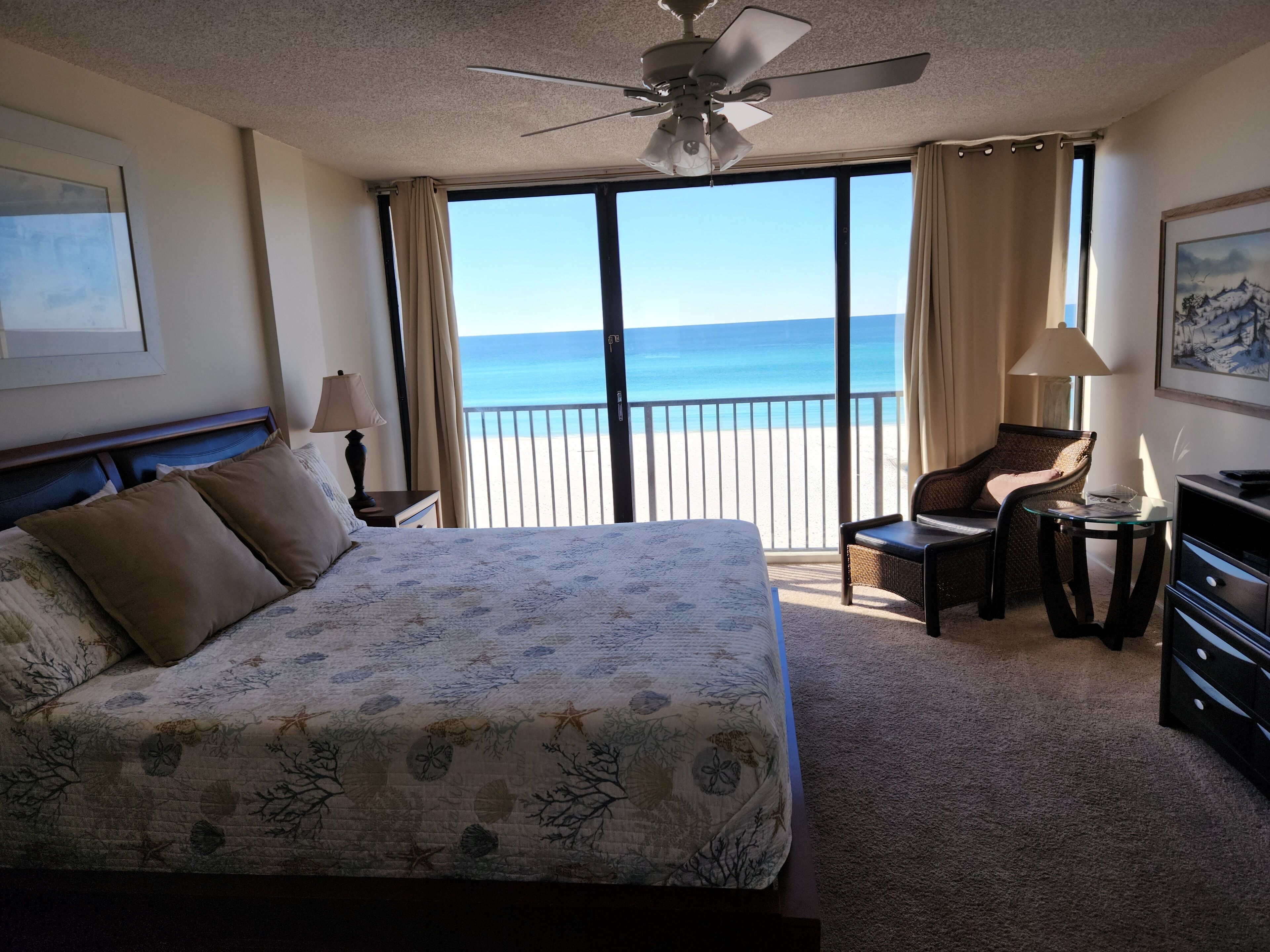 Une chambre d’hôtel avec un grand lit, une chaise, un bureau et une vue sur la plage.