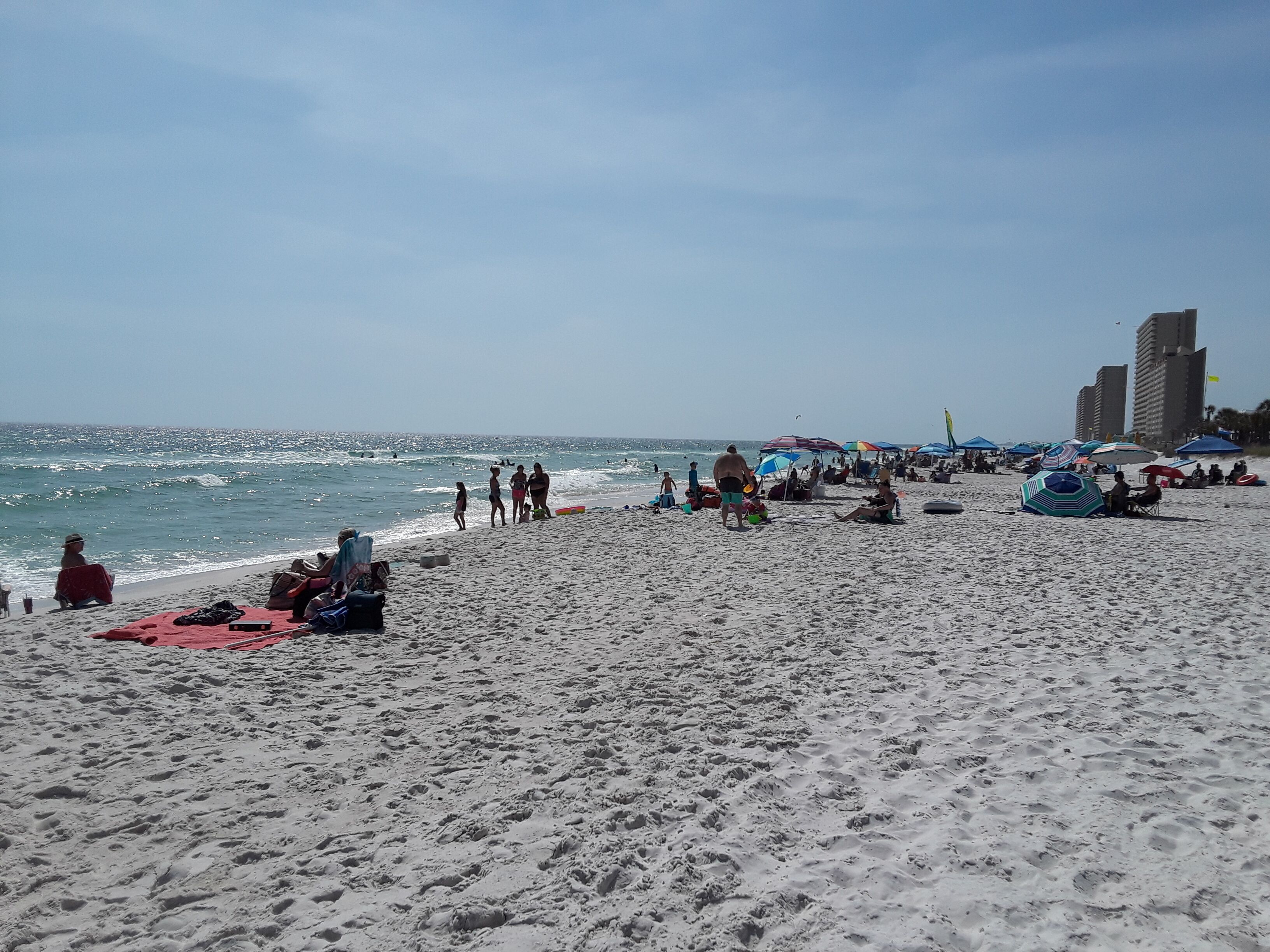 Una playa con gente, sombrillas y sillas de playa.