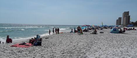 Una playa con gente, sombrillas y sillas de playa.