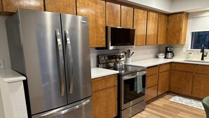 Una cocina moderna con electrodomésticos de acero inoxidable, armarios de madera, un microondas y una cafetera.