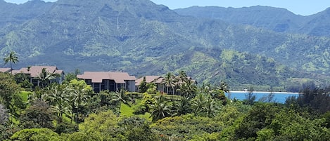 A resort with multiple buildings, lush greenery, and a mountain backdrop.