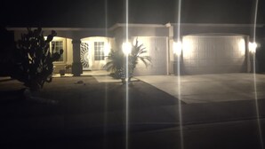 A residential house at night with a garage, illuminated by exterior lights.