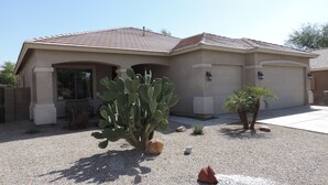 A residential building with a tiled roof, a cactus in the front yard, and a gravel driveway.