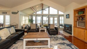 A spacious living room with a large window, a ceiling fan, a fireplace, and a bookshelf.