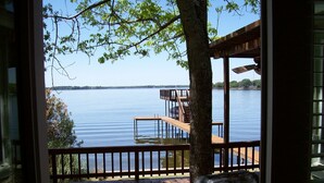A wooden deck with a view of a calm lake and a dock extending into the water.