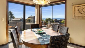 Een eetgedeelte met een ronde tafel, rieten stoelen en uitzicht op zee.