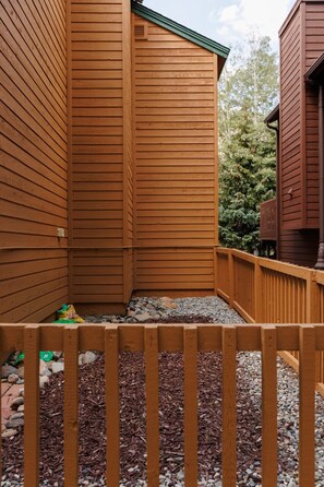 A wooden deck with a wooden fence, surrounded by a gravel area and mulch.