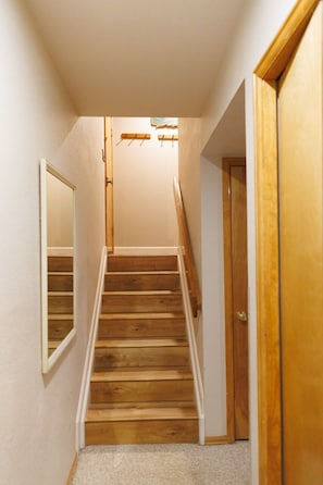 A wooden staircase leading to an upper floor, a door on the right, and a mirror on the left.