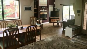 Ein Wohnzimmer mit Essbereich, Kamin, Fernseher und einem großen Fenster.