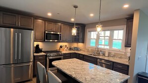 A modern kitchen with stainless steel appliances, granite countertops, and pendant lighting.