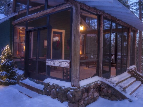 A rustic cabin with a gift shop sign, stone steps, and a snow-covered landscape.