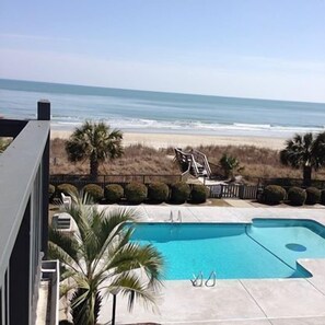 A pool with a view of the beach and ocean.