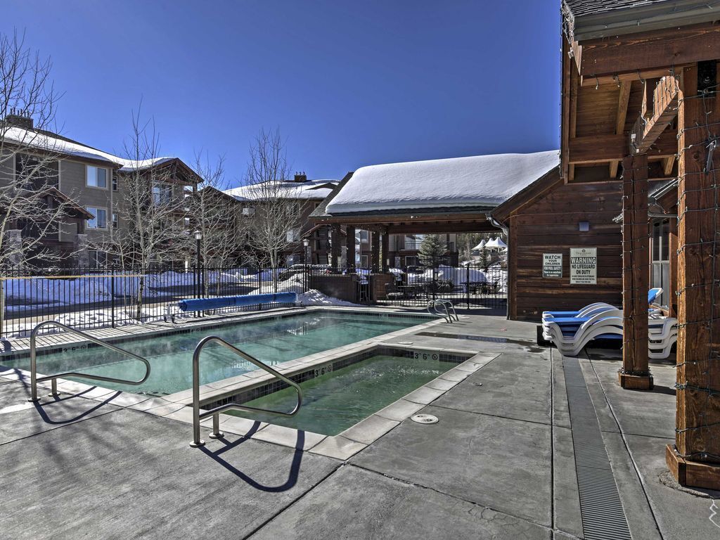 A pool area with a wooden deck, lounge chairs, and a covered seating area.