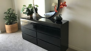 A black dresser with a large mirror, two potted plants, and a vase with flowers. - Look at This! Fun in the Sun for Everyone! (Kissimmee)