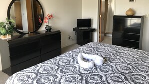 A bedroom with a bed, a dresser, a TV, and a mirror. - Look at This! Fun in the Sun for Everyone! (Kissimmee)