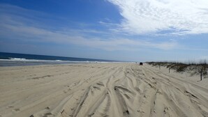 Ein Sandstrand mit Fußspuren und Dünen im Hintergrund.