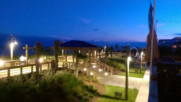 Nachtansicht eines Resorts mit einem hölzernen Pavillon, einem überdachten Gang und Blick auf den Ozean.