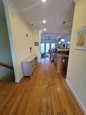 A spacious kitchen with wooden flooring, a dining area with a table and chairs, and a view of the living room through large windows.