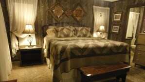 A bedroom with a bed, bedside tables, a bench, and a dresser.