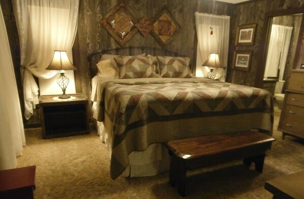 Une chambre à coucher comprenant un lit, des tables de chevet, un banc et une commode.