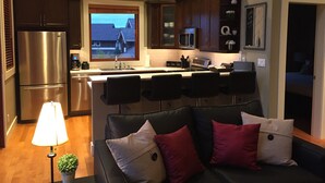 A modern kitchen with a built-in island, stainless steel appliances, and a view of a house through a window. - "Quails Run Retreat" on Bear Mountain  (Victoria)