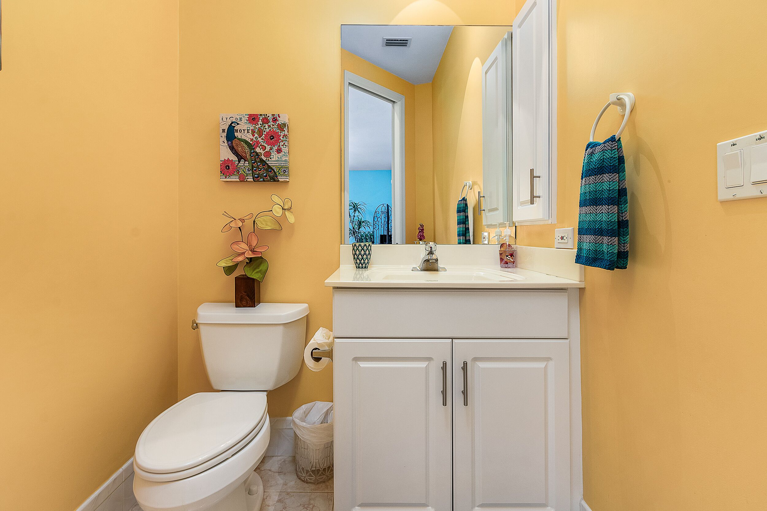 A bathroom with a toilet, sink, and cabinets.