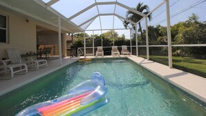 Una piscina con area coperta e lettini.