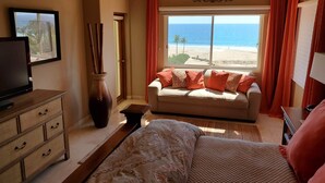 A bedroom with a bed, a sofa, a TV, a dresser, and a window with a beach view. - Las Mananitas, Fifth Floor, 3 Bedroom Villa, Oceanfront, HUGE Balcony.  (San Jose Del Cabo)
