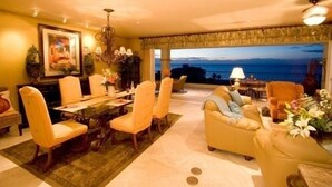 A spacious living room with a dining area, a chandelier, and a view of the sea. - Las Mananitas, Fifth Floor, 3 Bedroom Villa, Oceanfront, HUGE Balcony.  (San Jose Del Cabo)