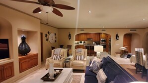 A spacious living room with a ceiling fan, a dining area with a chandelier, and a kitchen visible through an archway. - Las Mananitas, Fifth Floor, 3 Bedroom Villa, Oceanfront, HUGE Balcony.  (San Jose Del Cabo)
