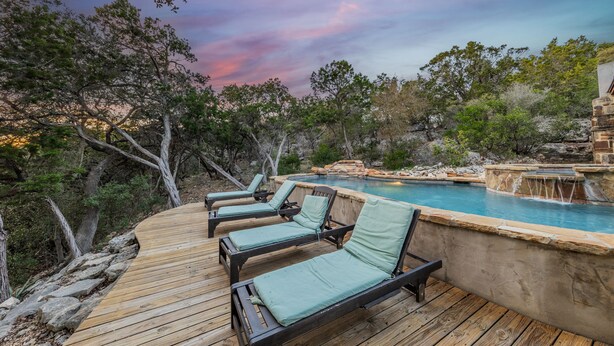 A wooden deck with lounge chairs and a pool with a waterfall feature. - Resort Quality 4B Home With Private Pool In Beautiful Hill Country (New Braunfels)