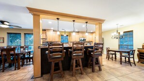 A kitchen with wooden cabinets, a central island with stools, and pendant lighting. - Resort Quality 4B Home With Private Pool In Beautiful Hill Country (New Braunfels)